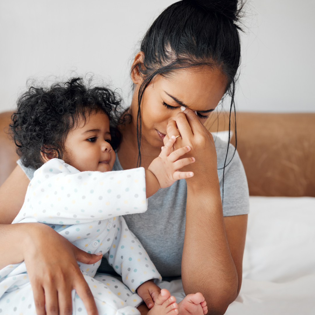 Postpartum mother experiencing a concerning headache while holding her baby