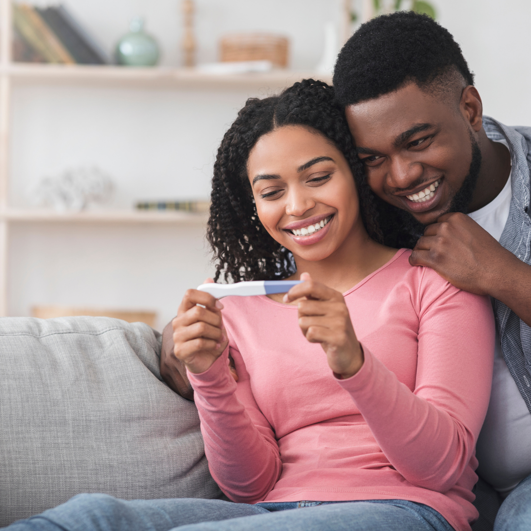 Couple smiling together while holding a positive pregnancy test