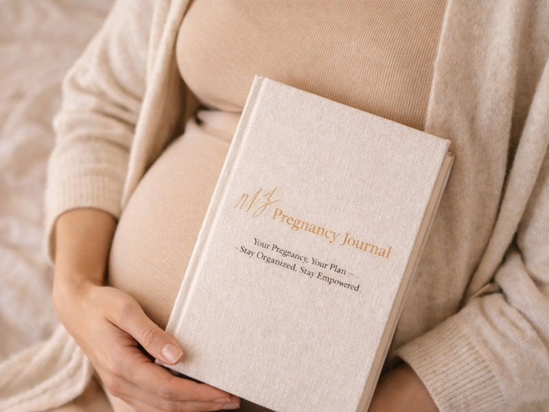 Person holding a beige pregnancy journal with text on it.